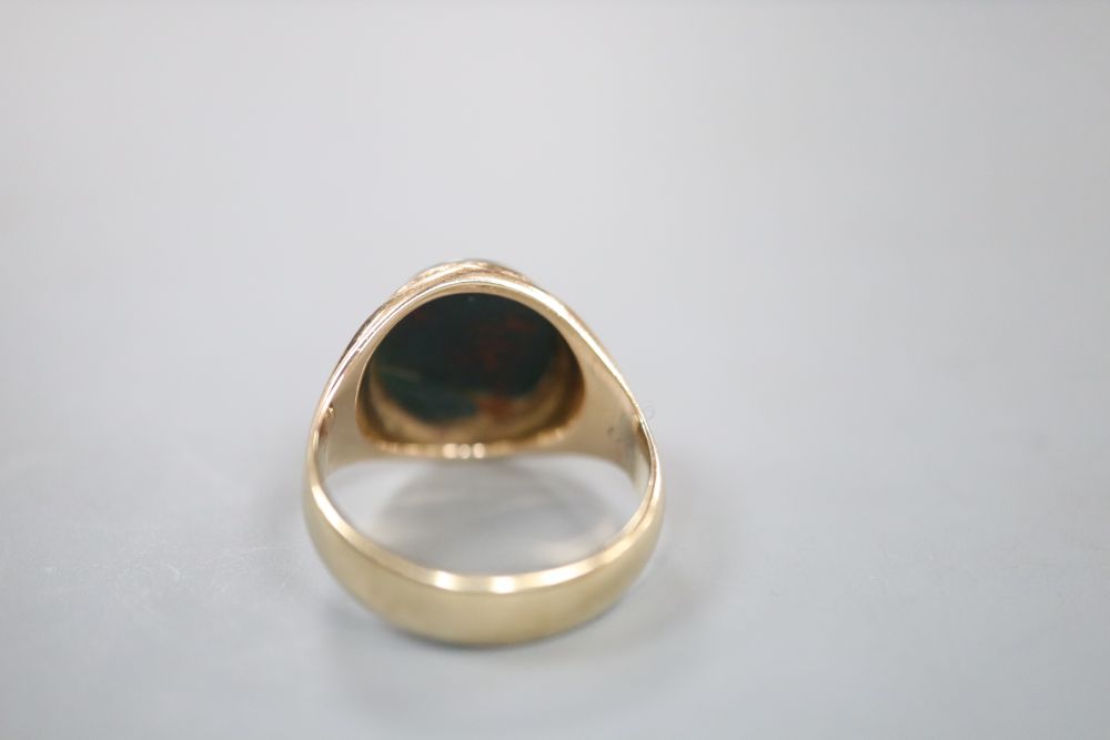 A 9ct and carved crested oval bloodstone set signet ring (stone a.f.), size K, gross 4.5 grams.